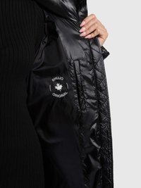 Giacca trapuntata nera con esterno in nylon lucido. Presenta un'etichetta interna con il logo ("KHUJO ORIGINAL") e tasche laterali. Texture liscia.