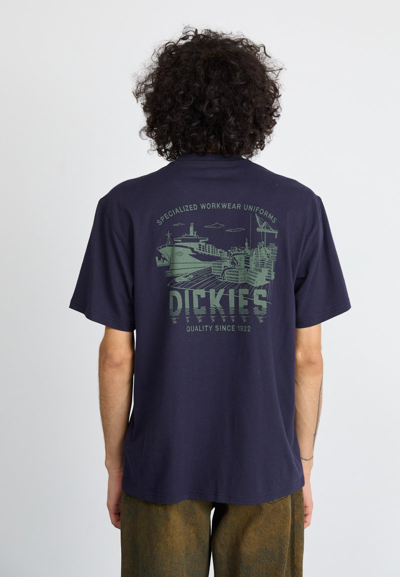 Tamsiai mėlyna trumpomis rankovėmis marškinėliai su žaliu laivo grafiniu dizainu ir tekstu "Dickies" nugaroje. Tekstūruota medvilnė.