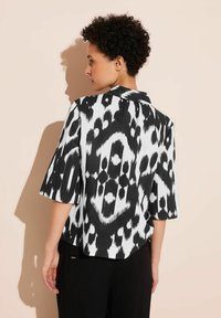 Short-sleeve shirt in black and white ikat print; features a collared neck and a relaxed fit with a textured fabric.