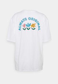 Biele oversized tričko s farebným kvetinovým vzorom na chrbte, s textom "VŽDY ORIGINÁL" v modrej farbe nad kvetinami.