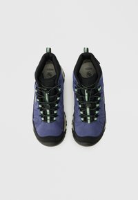 Zapatos de senderismo morados con acentos negros, parte superior texturizada, cordones a rayas verdes y negros, y suelas de goma robustas para una buena tracción.