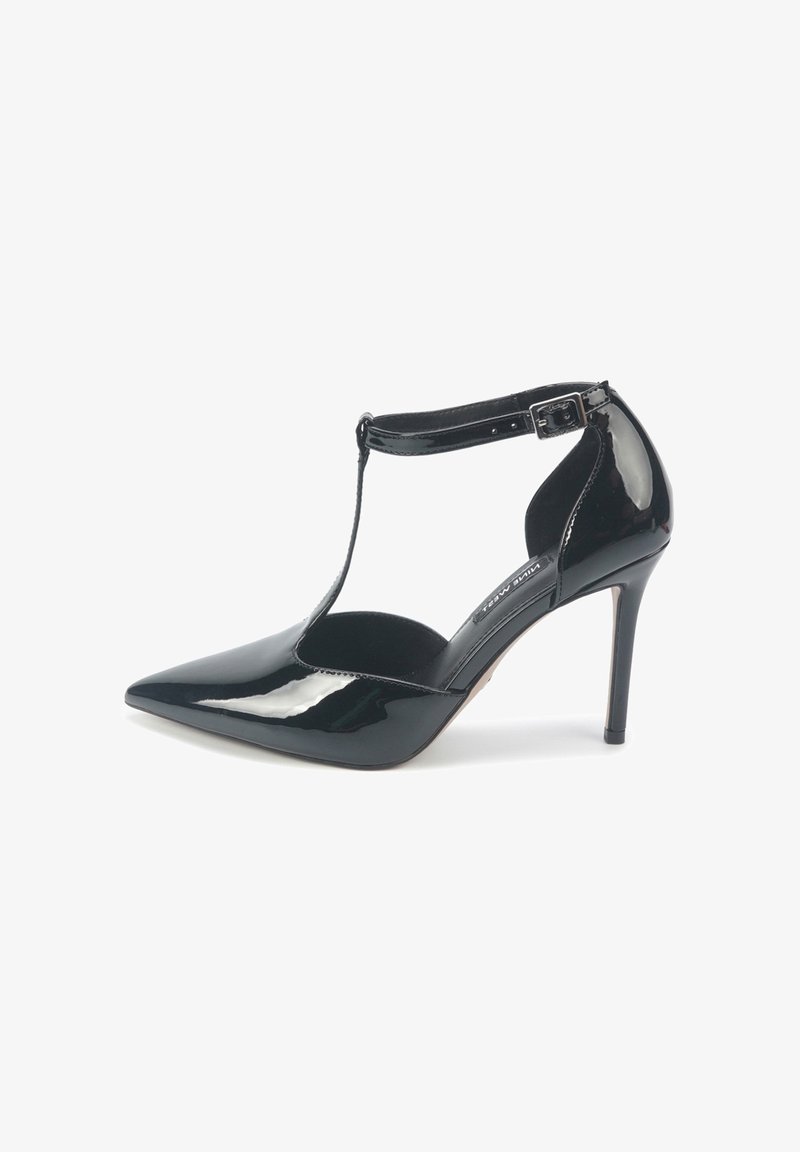 Scarpa con tacco alto in pelle verniciata nera, punta affusolata, design T-strap, fibbia alla caviglia e finitura lucida e liscia.