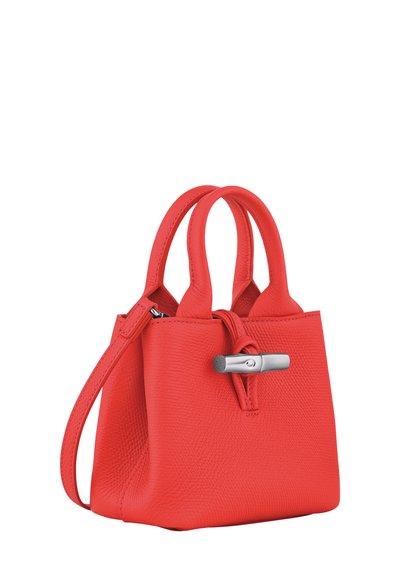 Small red textured leather handbag with double handles, detachable shoulder strap, and silver toggle closure on front.