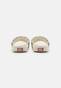 White sandals with black accents, featuring a contoured design, open toes, and a textured footbed. Brand logo visible on the heel.