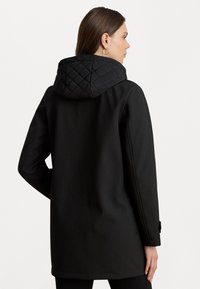 Manteau noir avec une capuche matelassée noire, à manches longues et coupe droite. Présente une texture lisse et des accents de boutons aux poignets.
