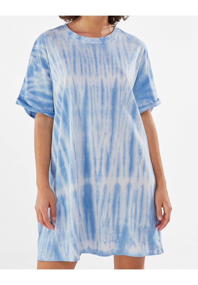 Svetle modré šaty s tie-dye vzorem vyrobené z měkké bavlny, s kleslými rameny, krátkými rukávy a volným střihem s kulatým výstřihem.
