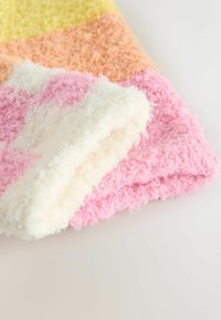Flauschige Wohndecke in Pastellfarben: Gelb, Orange, Rosa und Weiß. Sie zeichnet sich durch eine weiche Textur und abwechselnde Farbblöcke mit einem gemütlichen Gefühl aus.