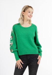 Maglione verde con scollo rotondo, maniche lunghe decorate con cuori in paillettes dorate e orlo a costine. Tessuto a maglia strutturato.