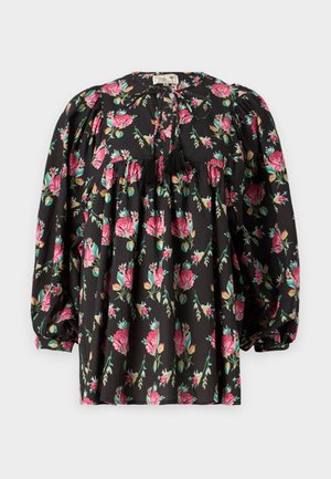 Blouse noire avec un motif floral en rose et vert. Comprend des manches bouffantes, un buste froncé et un lien avec des pompons au niveau du col.