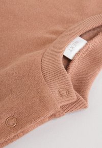 Hele roosa kootud kampsun soonikkoega kraega ja nööriaktsentidega. Kaeluse juures on nähtav silt. Pehme, tekstuuriga kangas.