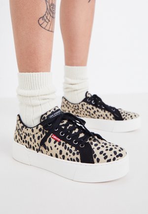 Baskets imprimées léopard beiges avec lacets noirs, semelle blanche et étiquette rouge Levi's. Tissu texturé avec un design plat et une pointe ronde.