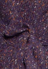 Ręcznie dziergany szalik z fioletowej włóczki z wielokolorowymi plamkami. Posiada detal w postaci zawiązanego węzła, ukazujący teksturę i przytulny wygląd.