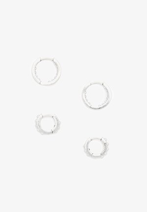 Vier zilveren oorbellen in de vorm van hoepels van verschillende maten; sommige hebben kleine kraalaccenten en tekstdetails, met een gladde, gepolijste afwerking.