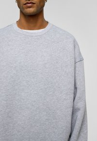 Grijze sweatshirts van een gestructureerde stof, met een ronde halslijn en doorgezakte schoudernaden. Heeft een relaxte pasvorm en minimale details.