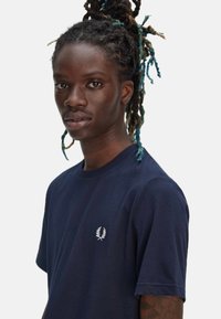 Camiseta de algodón de color marino con mangas cortas, cuello redondo y logotipo bordado en blanco en el lado izquierdo del pecho. Textura suave, corte clásico.