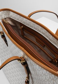 Beige Baumwolltasche mit braunen Kunstlederakzenten. Verfügt über ein geräumiges Innenleben, Reißverschlussfächer und farblich abgestimmte Griffe.