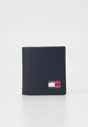 Navy blue leather wallet with a textured surface, featuring a small rectangular "TOMMY JEANS" logo in red, white, and blue on the front.