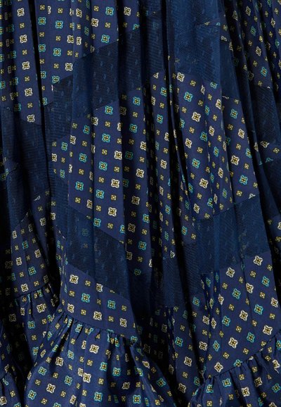 Tessuto blu navy con un motivo geometrico in verde, azzurro chiaro e bianco. Il design testurizzato presenta volant e pannelli di tessuto di vario tipo.