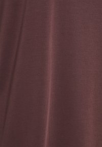 Burgundytyg med en jämn och slät yta; lätt och något elastiskt. Inga påtagliga mönster eller ytterligare detaljer närvarande.