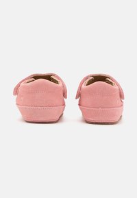 Roosa suede jalanõud pehme tekstuuri, ümar kuju ja takjapaelidega. Seljaosa esitleb puhtat, minimalistlikku disaini, millel on õmmeldud õmblus.