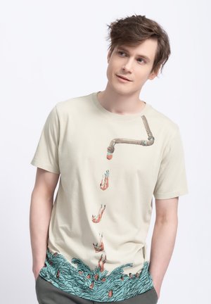 Beige cotton t-shirt featuring a pipe design that drips stylized figures into turquoise waves at the hem. Short sleeves, relaxed fit.