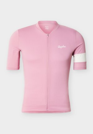Maillot de cyclisme rose à manches courtes avec fermeture éclair frontale, logo blanc sur la poitrine, bande blanche sur la manche gauche et motif texturé du tissu.