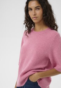 Rosa fluffiger Strickpullover mit Rundhalsausschnitt und kurzen Ärmeln, mit lockerem Schnitt und leicht geöffneten Seitennähten.