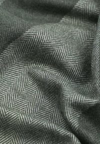 Visgraatpatroon stof in tinten grijs en groen, met een zachte, gestructureerde oppervlakte en een duidelijk zichtbaar weefsel en diepte.