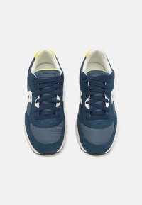 Navy blue sneakers with mesh and suede materials, featuring white accents, yellow heel tab, and laces. Classic design with rounded toe.