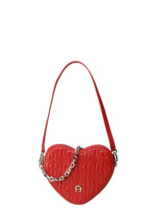 Rote handtasche in herzform mit gesteppter oberfläche, goldener kettendetail und rotem schulterriemen auf weißem hintergrund.