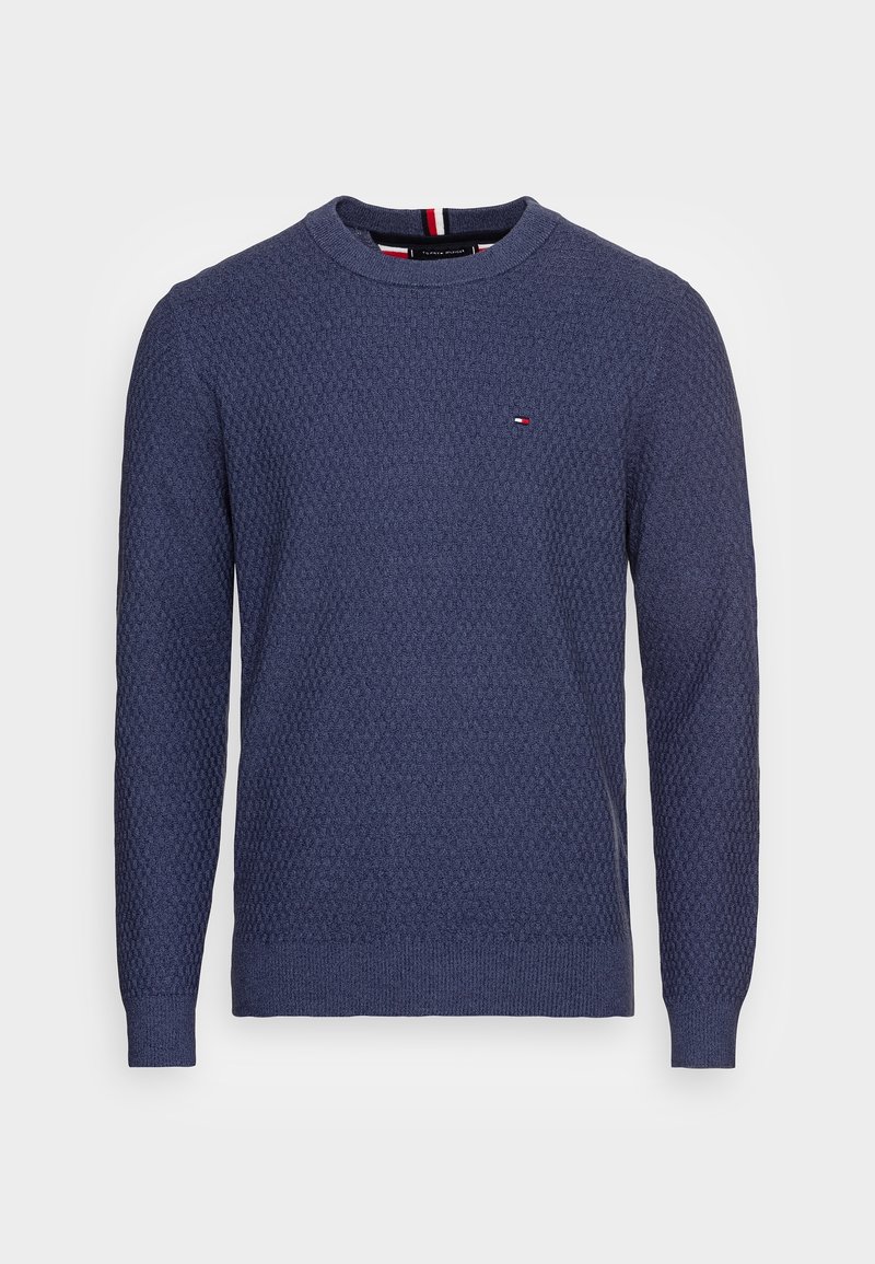Pull en maille bleu marine à manches longues avec col rond, petit logo rouge, blanc et bleu sur la poitrine gauche, poignets et ourlet côtelés.