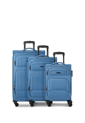 Three blue soft-shell suitcases of different sizes with black telescopic handles and four black spinner wheels, arranged side by side.