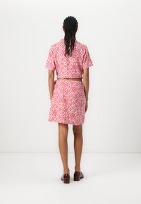 Robe à manches courtes, à motifs rose et blanc, mettant en valeur une taille ajustée et une jupe évasée. Tissu lisse et imprimé géométrique subtil.