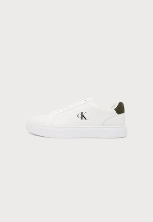 Λευκό αθλητικό παπούτσι τύπου low-top με λευκή σόλα, μαύρο λογότυπο "cK" στην πλευρά και σκούρο πράσινο τακούνι από σουέτ σε απλό φωτεινό φόντο.