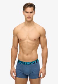 Boxer in microfibra a righe blu con elastico nero a tinta unita, con la scritta azzurra "SUPERDRY". Tessuto liscio ed elastico, design aderente.