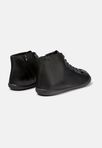 Botas de cuero negro hasta el tobillo con acabado texturizado, punta redonda, cordones azules y cremallera lateral. Forma ajustada con una suela de contraste.