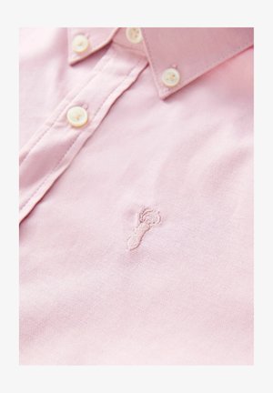 Camisa de algodón rosa claro con cuello abotonado, con botones blancos y un pequeño diseño bordado de una langosta en el pecho.