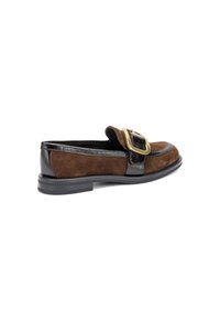 Mocasines de ante marrón con un elegante ribete de cuero negro brillante y un gran detalle de hebilla dorada en la parte superior. Suela plana de goma.