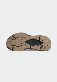 Semelle extérieure en caoutchouc beige et noir à crampons d'une chaussure de randonnée, avec des crampons profonds pour une bonne adhérence et le logo The North Face embossé au centre.