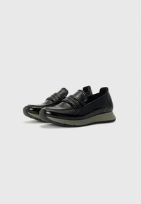 Black patent leather loafers with a rounded toe and decorative strap. Features a cushioned grey sole for comfort and flexibility.