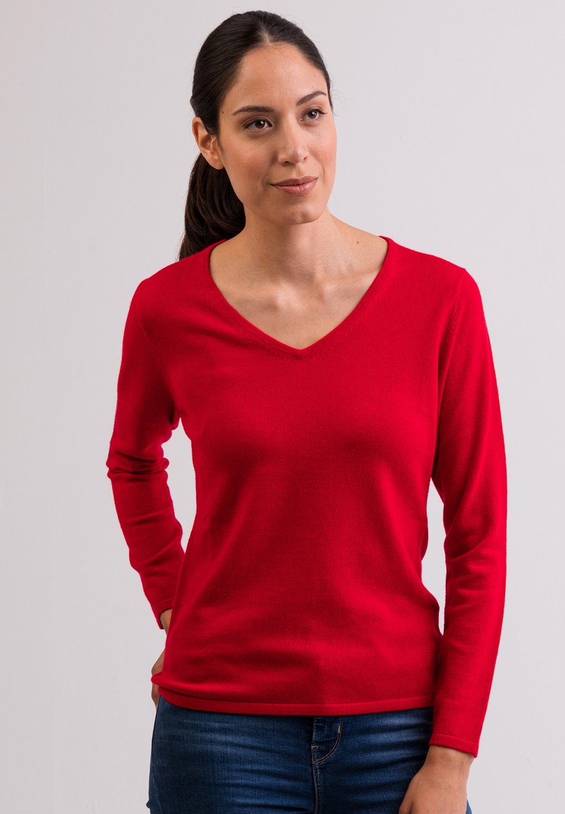 Roter langärmeliger V-Ausschnitt-Pullover aus weichem Material, figurbetonte Silhouette, mit glatter Textur und geripptem Saum. Getragen mit blauen Jeans.