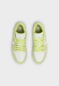 Paire de baskets basses blanches et vert clair avec lacets, vues de dessus sur un fond gris clair.