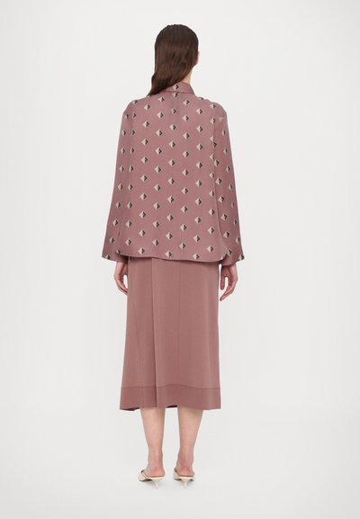 Langermet, rosa bluse med geometrisk mønster i svart og beige; kombinert med et matchende midiskjørt; glatt stoff og rikelig passform.