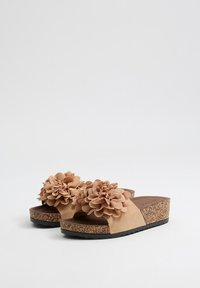 Sandalias de plataforma de yute con dos grandes acentos en forma de flores de tela, parte superior de ante texturizado, entresuela de corcho y suela de goma negra para mayor agarre.