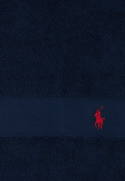 Donkerblauw textuurstof met een horizontale band waarop een kleine rode geborduurde figuur van een polo-speler te paard staat.