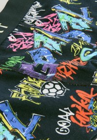 Svart tygunderkläder med livliga graffiti-mönster i färger som grön, blå, rosa och orange, med en detalj av en fotboll.