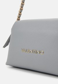 Borsa a spalla in pelle grigia con finitura testurizzata, caratterizzata da un logo in tonalità oro e dettagli con catena.