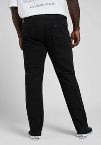 Czarne dżinsy w prostym kroju, z tylnymi kieszeniami i teksturowanym wykończeniem. W połączeniu z czarno-białymi sneakersami.