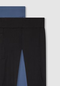 Czarne i niebieskie leginsy, zestawione ze sobą, z szerokim pasem w talii, gładką fakturą i małym detalem kieszeni w czarnej parze.