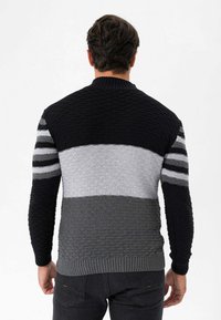 Knitted sweater featuring a textured design. Colors include black, grey, and light grey with horizontal stripes on the sleeves. Ribbed cuffs and hem.